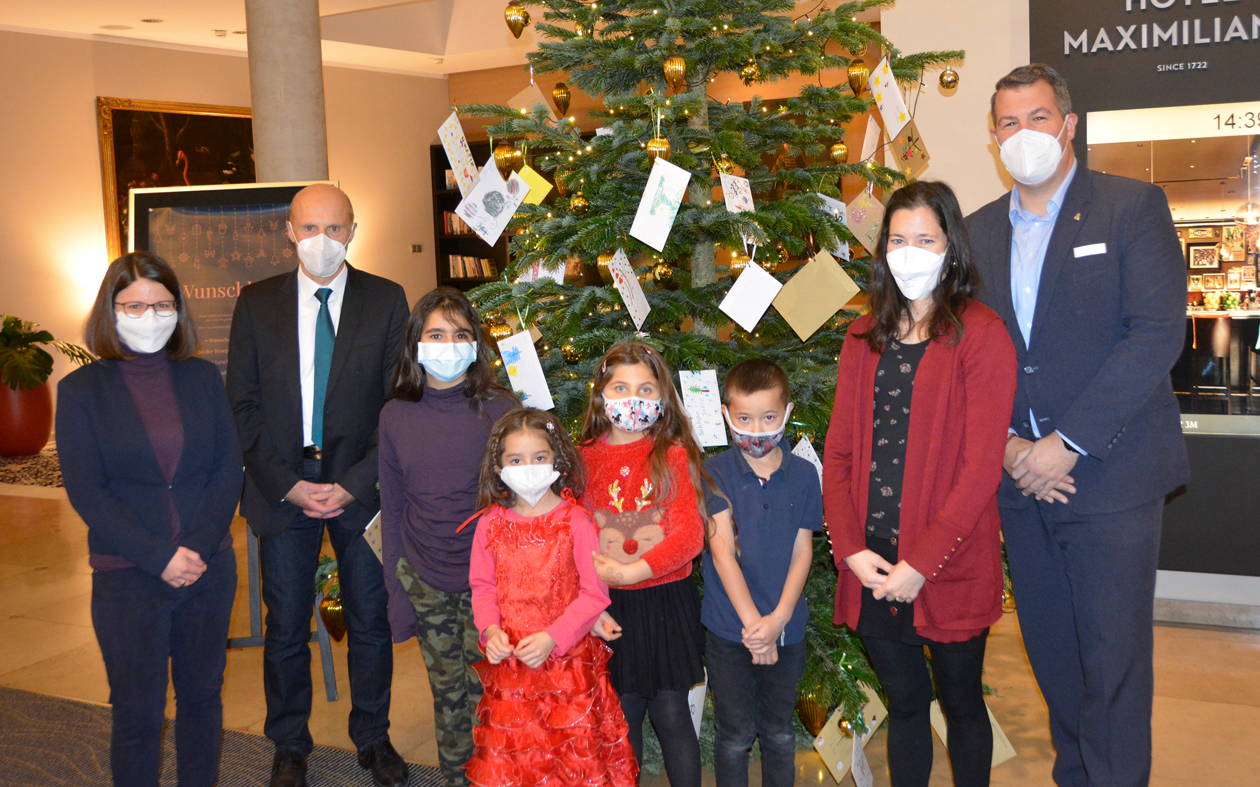 Mit den Kindern des Frère-Roger-Kinderzentrums den Wunschbaum schmücken, von links: Nadja Galanti (Frère-Roger-Kinderzentrum), Markus Mayer (Vorstandsvorsitzender KJF Augsburg), Meryem Meinusch (Familienzentrum Peter & Paul), Sascha Eckl (Maximiian`s). Foto: KJF Augsburg/Jasmin Mächtlinger