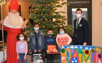 Die Kinder des Frère-Roger-Kinderzentrums gestalteten als Dankeschön ein großes und farbenfrohes Plakat für das Hotel Maximilian's. Von links: Der heilige Nikolaus und Hotel-Manager Michael Artner. Foto: KJF Augsburg / Jasmin Mächtlinger