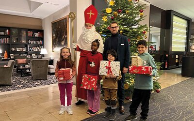 Glückliche Gesichter bei der Geschenkübergabe der Wunschbaum-Aktion im Hotel Maximilian’s: Der Nikolaus und Thomas Richter (hinten rechts), Assistant Marketing Manager am Hotel Maximilian's, freuen sich mit den Kindern. Foto: KJF Augsburg / Johanna Batjargal